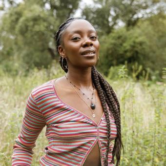 Earth Minutes event speaker, Joycelyn Longdon, standing in a meadow looking at the camera